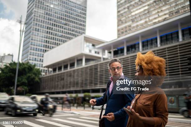 des collègues parlent et marchent dans la rue - traverser photos et images de collection