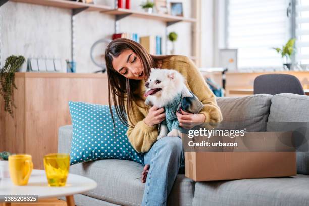 young woman unpacking a package for her dog - pomeranian puppy stock pictures, royalty-free photos & images