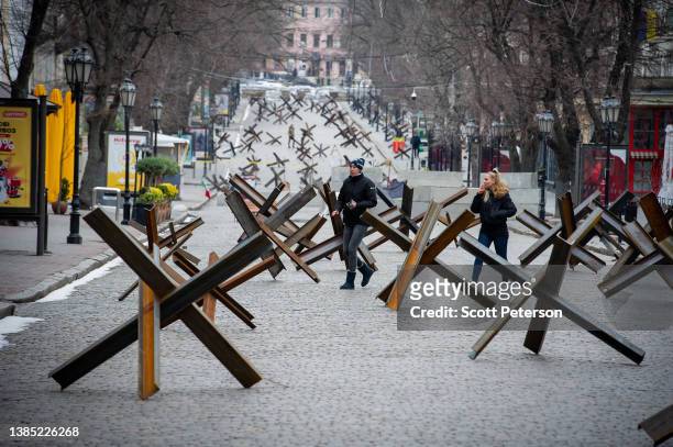 People walk among anti-tank barriers placed to protect historic landmarks in expectation of a Russian assault on the strategic Black Sea port city on...