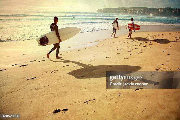 surfers walking along manly beach - manly beach stock pictures, royalty-free photos & images