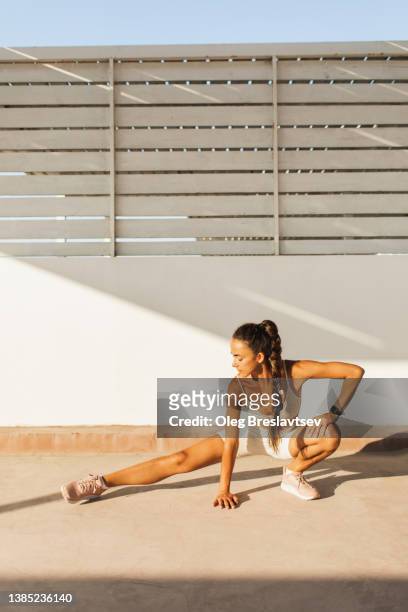 athletic sportive woman stretching legs and warming up body before interval tabata workout. female health - extreme dieting stock pictures, royalty-free photos & images