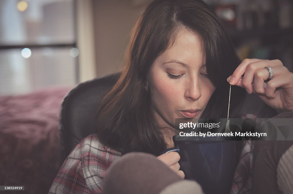 Woman blowing on hot cup of tea