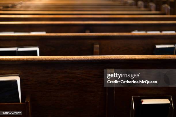 rear view of rows of wooden pews with religious liturgy books stored in pew racks in church - minister clergy ストックフォトと画像