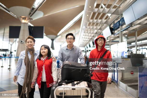familia china asiática caminando con sus hijos y equipaje por la terminal del aeropuerto. - family at airport fotografías e imágenes de stock