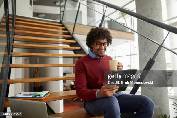 african american businessman working on the stairs using digital tablet - electronic organizer stock pictures, royalty-free photos & images