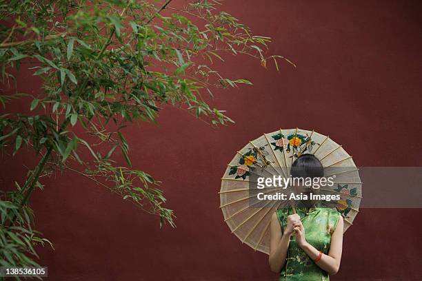 young woman wearing a traditional chinese dress holding an umbrella - abito tradizionale cinese foto e immagini stock