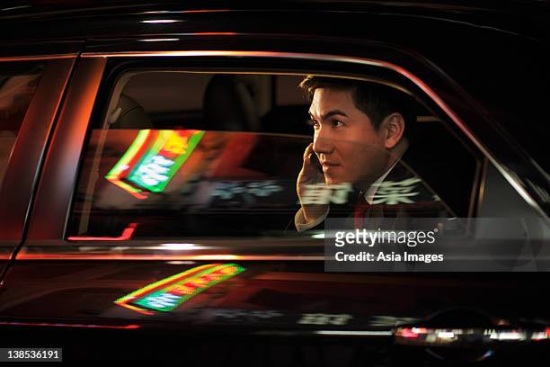 man sitting in car talking on phone. chinese characters reflected on the windows - mobility windows phone stock pictures, royalty-free photos & images