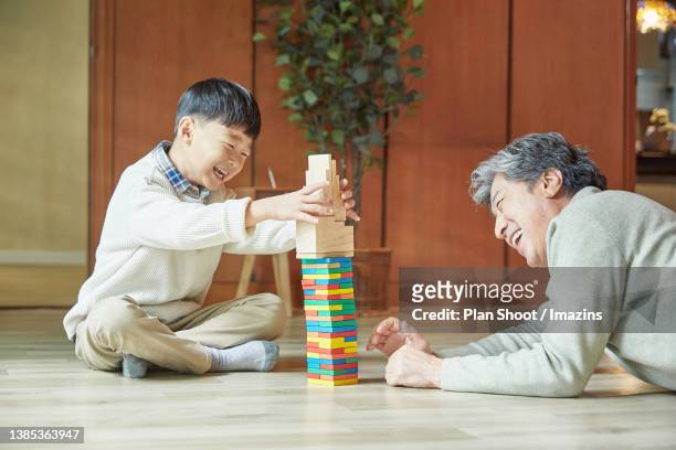 grandfather and grandson playing building game together - jenga stock pictures, royalty-free photos & images