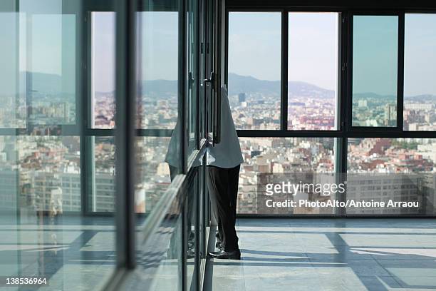 man leaning out of window looking at city - bay window stock pictures, royalty-free photos & images