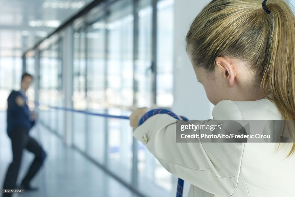 Businesswoman playing tug-of-war, rear view