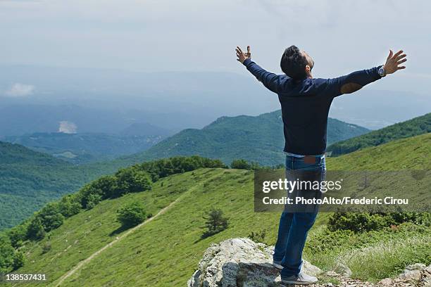 man standing on top of rock with arms outstretched, rear view - head back stock pictures, royalty-free photos & images