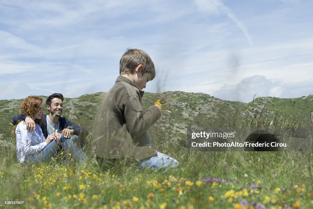 Parents and young boy sitting on meadow