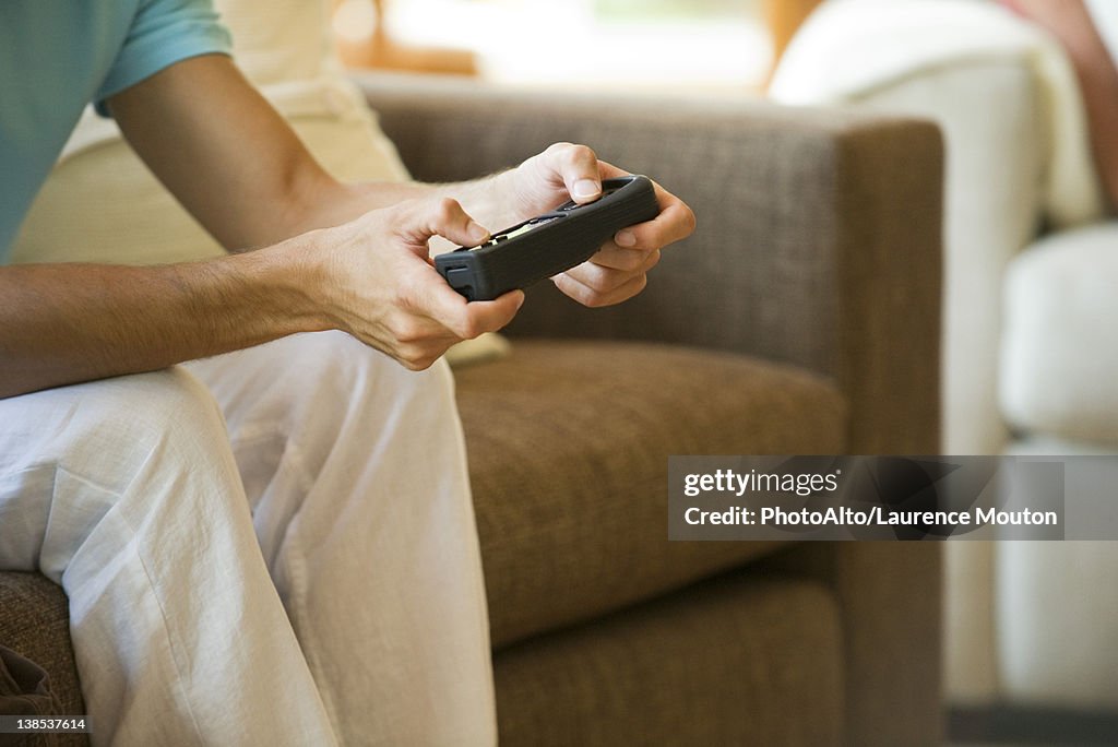 Man playing video game using wireless controller, cropped