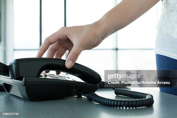 woman picking up telephone receiver, backlit, cropped - telephone receiver fotografías e imágenes de stock