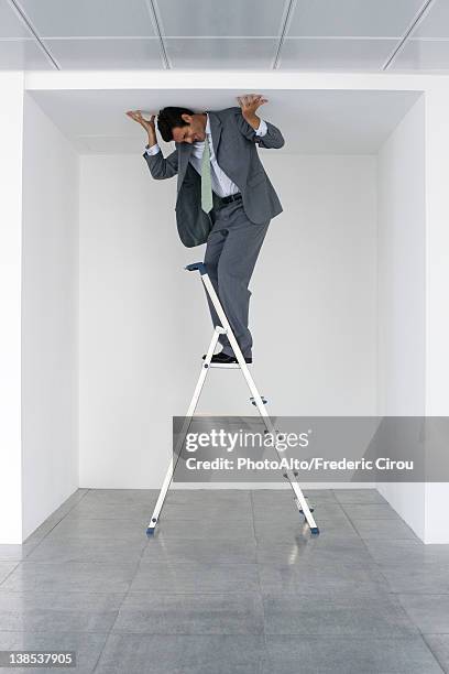 executive standing on stepladder, pushing ceiling - step ladder stock pictures, royalty-free photos & images