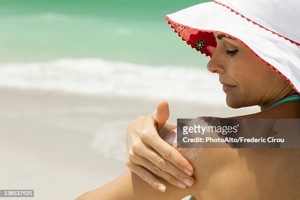 woman at the beach applying sunscreen - applying sunblock stock pictures, royalty-free photos & images