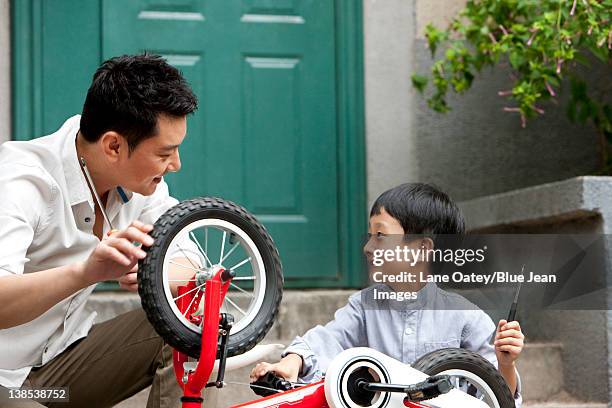 young chinese father and son fixing bike - kid cheering stock pictures, royalty-free photos & images