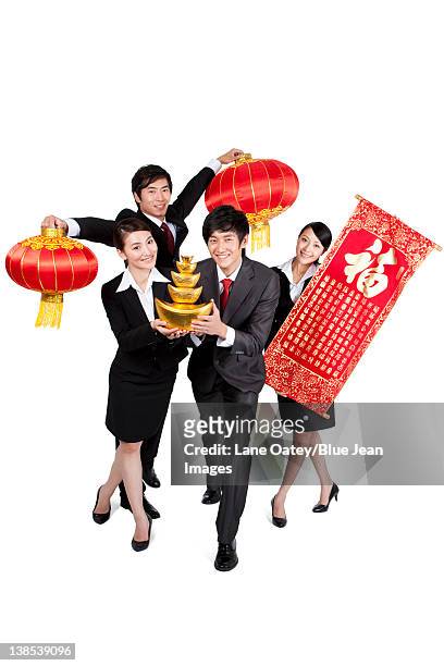 business colleagues holding up chinese new year decorations - business woman in red suit jacket stock pictures, royalty-free photos & images