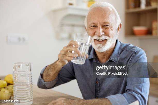 senior mann trinkwasser - wasser trinken zu hause stock-fotos und bilder