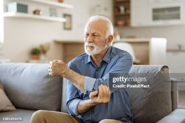 senior man with elbow pain - ontsteking medische aandoening stockfoto's en -beelden