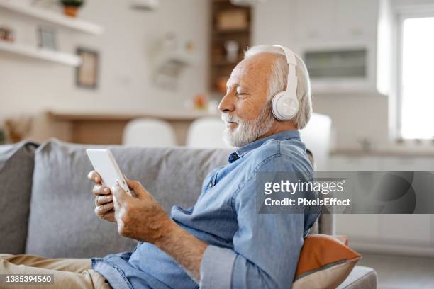 senior man with headphones and digital tablet - watching youtube stock pictures, royalty-free photos & images