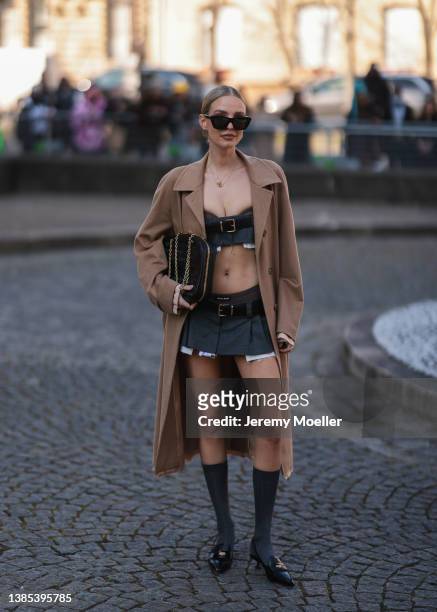Leonie Hanne seen wearing gold chain necklaces, black sunglasses, black monogram earrings from Miu Miu, a dark grey ripped shoulder-off / cropped top...