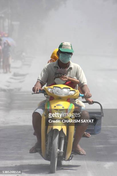 Family ride on a motorcycle thorugh ash in the Philippine town of Irosin, Sorsogon province on February 21, 2011. A Philippine volcano erupted...