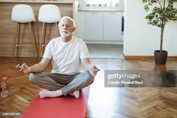 senior fitness mann macht meditation - senior yoga stock-fotos und bilder