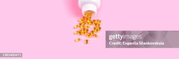 web banner with fish oil supplements in a white bowl on pink background. - huile de foie de morue photos et images de collection