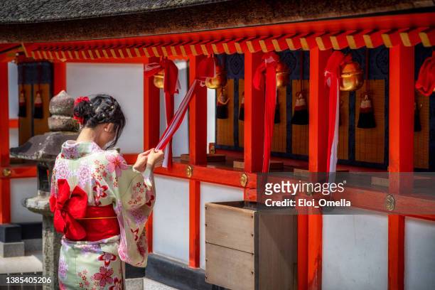 praying at fushimi inari taisha shrine in kyoto - inari shrine stock pictures, royalty-free photos & images