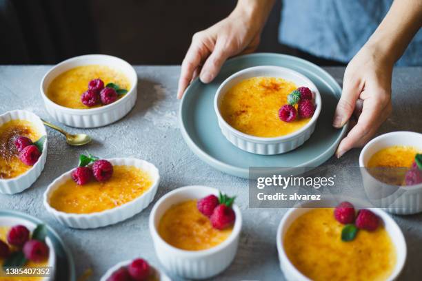 close-up of a woman serving homemade creme brulee - creme brulee stock pictures, royalty-free photos & images