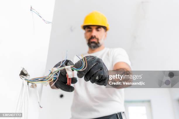 elektriker bei der arbeit auf der baustelle - electromonteur stock-fotos und bilder