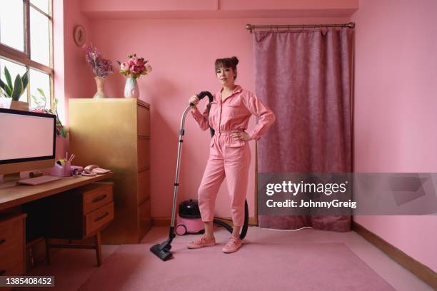 full length portrait of woman cleaning pink home interior - excentriek stockfoto's en -beelden