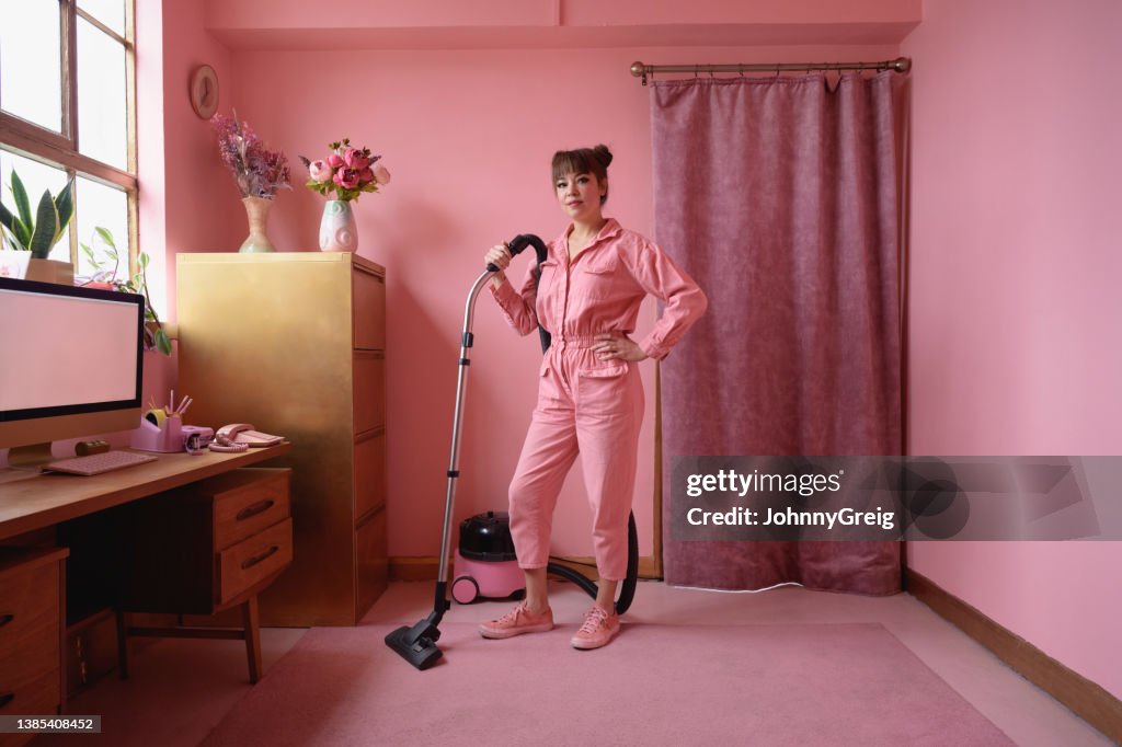Full length portrait of woman cleaning pink home interior