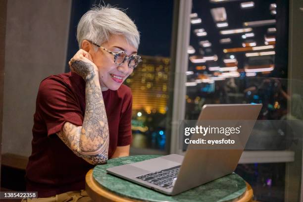 senior woman with technology. daily life at night. - old woman tattoos stock pictures, royalty-free photos & images