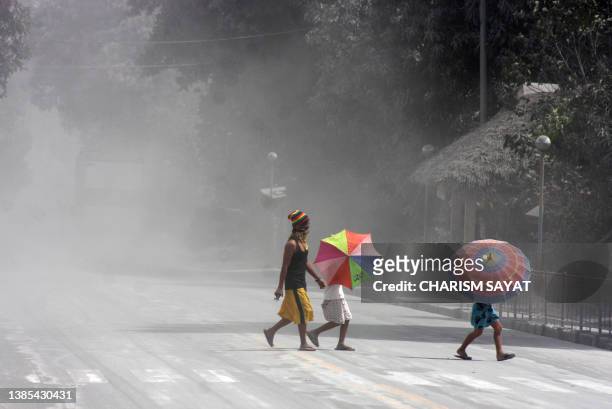 People walk thorugh ash as they cross a road in the Philippine town of Irosin, Sorsogon province on February 21, 2011. A Philippine volcano erupted...