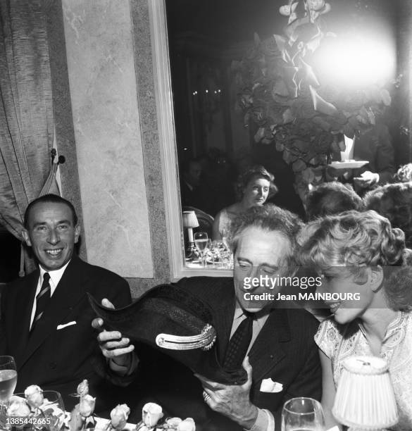 Jean Cocteau et Jacqueline Pagnol célébrant le Disque d'Or de Charles Trenet au restaurant 'Maxims', en octobre 1955, à Paris.