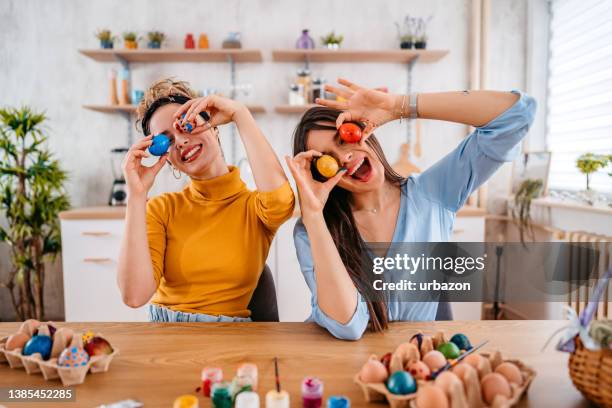 dos mujeres jóvenes sosteniendo huevos de pascua - pascua fotografías e imágenes de stock