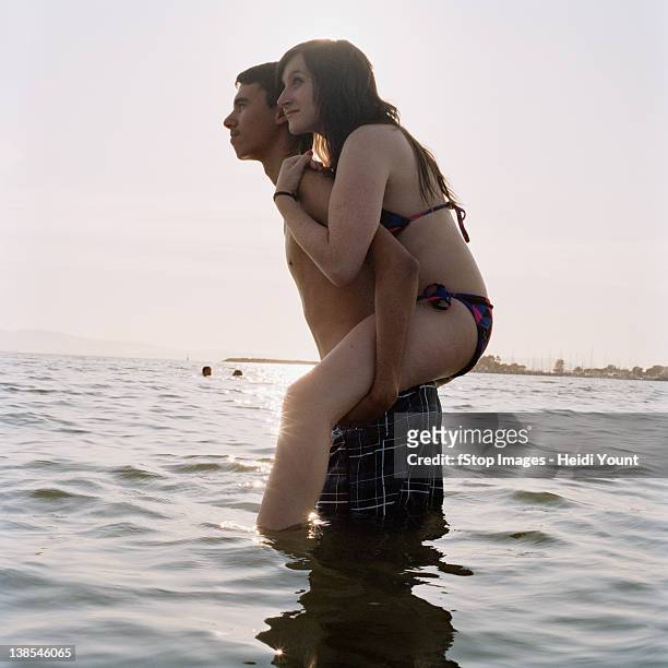 a young man giving his girlfriend a piggyback ride in the sea - alameda california stock pictures, royalty-free photos & images
