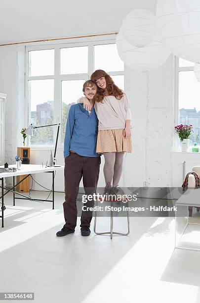 a young women standing on a stool next to her tall boyfriend - short guy tall woman stock pictures, royalty-free photos & images