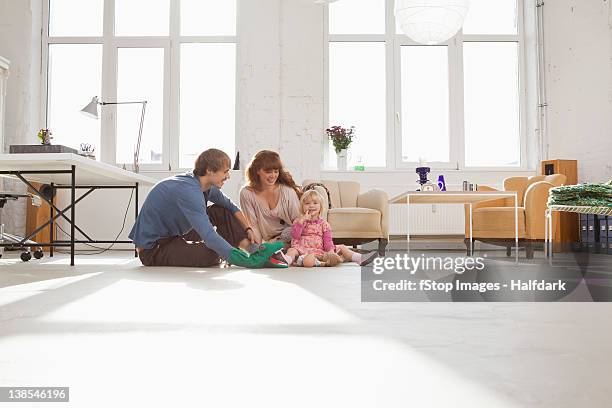 a young hip family playing together on living room floor - sitting on floor fotografías e imágenes de stock