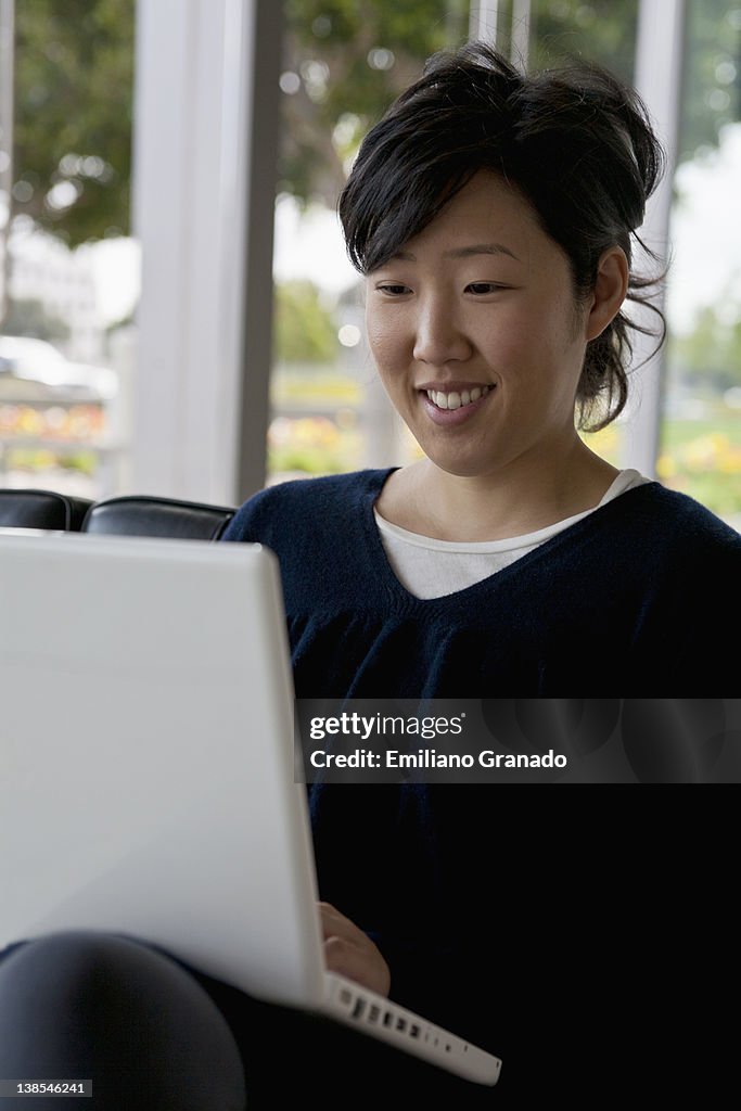 A young woman sitting on a sofa using a laptop