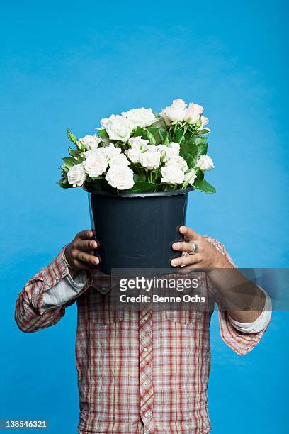 man holding black bucket of flowers in front of his face - bucket stock-fotos und bilder