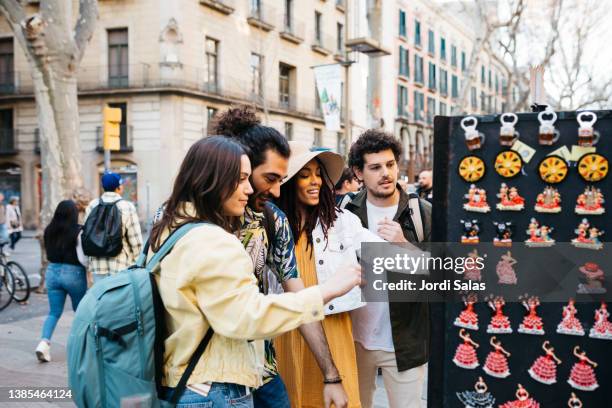 tourists watching souvenirs in barcelona - souvenir de vacances photos et images de collection
