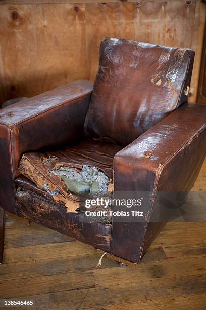 an old weathered leather armchair with torn cushion - tear face photos et images de collection