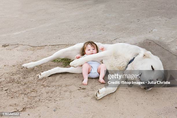 A baby lying with a dog