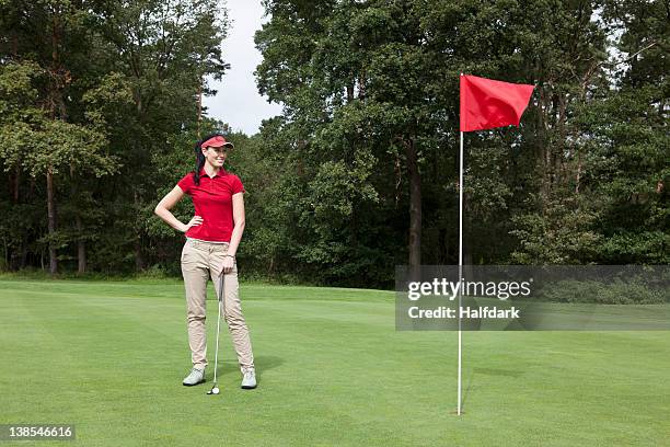 a female golfer standing on a putting green - golf flag stock pictures, royalty-free photos & images
