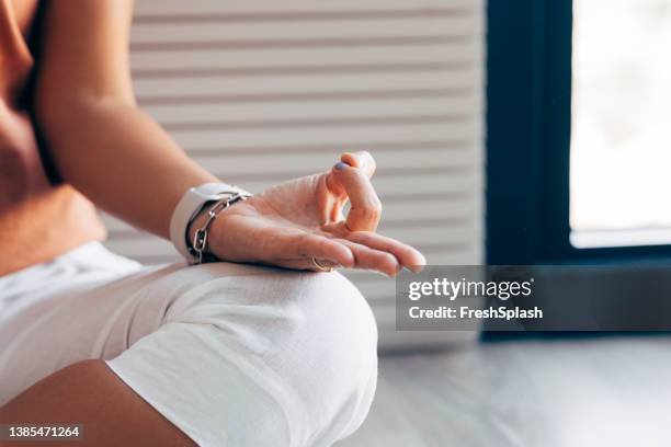 anonyme hand einer frau in einer gyan mudra-position, während sie in lotus-pose sitzt und meditiert - lotussitz stock-fotos und bilder