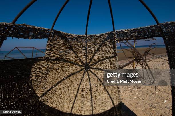 Beach umbrellas, rusted and toppled by time and neglect, scatter the beach in front of an abandoned tourist resort in Nuweiba, Egypt on August 02,...