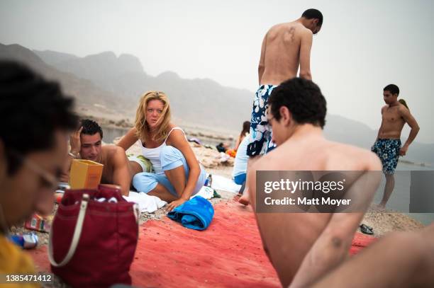 European woman sits on the beach with her Egyptian boyfriend and other Egyptian men near Nuweiba, Egypt on April 26, 2008.